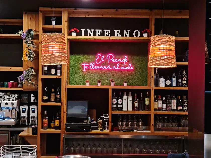 A barra de madeira coas botellas e o neón rosa sobre o xardín vertical